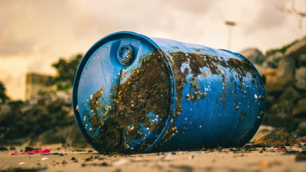 blue plastic barrel with mud on the ground